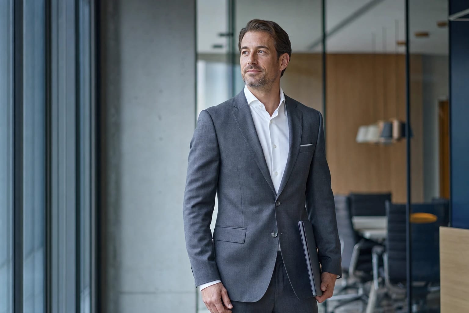 KI-generiertes Bild: Führungskraft im grauen Anzug steht ruhig und souverän in einem modernen Büro – Businesscoaching für Führungskräfte.