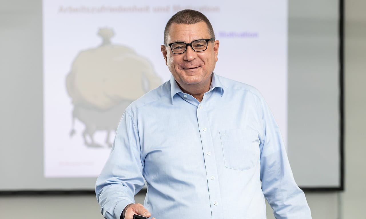 Alexander Preidt vor einer Präsentationsfolie zu Arbeitszufriedenheit und Motivation